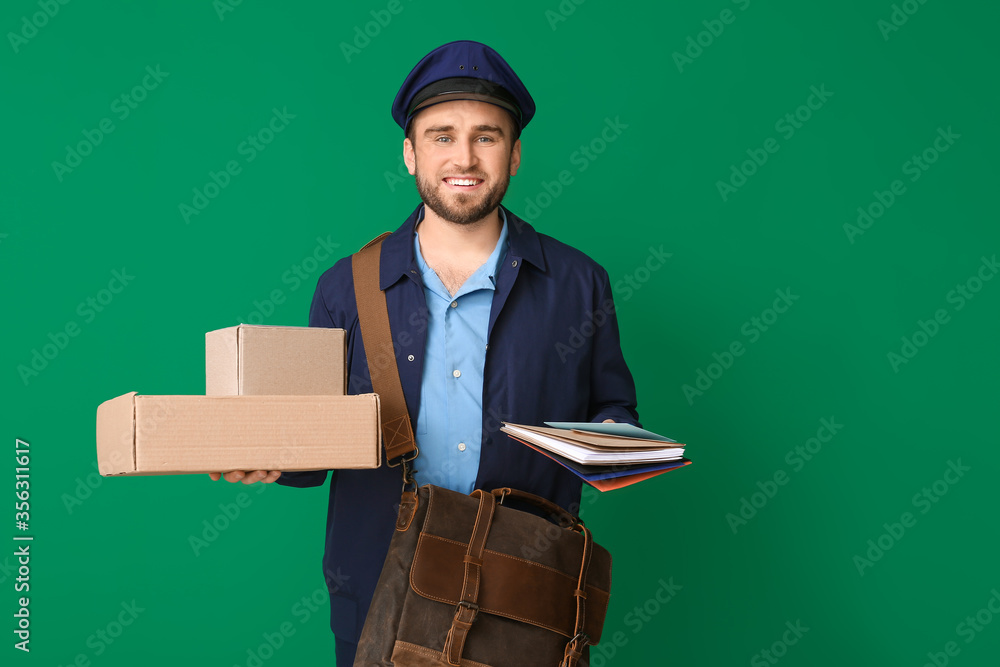 Handsome young postman on color background