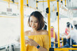 © makistock - Portrait of young Asian woman using phone and standing on the bus/ public transportation.