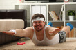 © H_Ko - Young attractive fitness man lies on a fat mat with overweight performs exercises and smiles