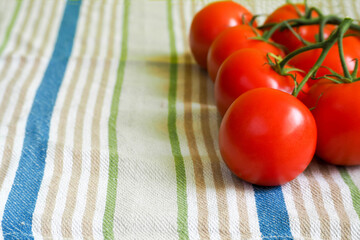 red round tomatoes on a striped linen tablecloth side view . raw red tomatoes macro