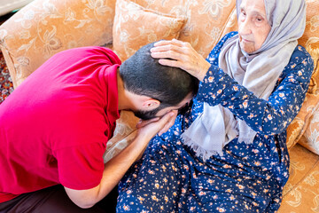 Arabic muslim guy kissing his grand mother hand out of respect