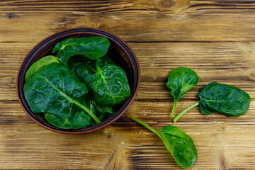 Poster - Fresh green spinach leaves in bowl on a wooden table. Top view