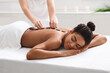 Relaxed african woman getting hot stone massage at spa