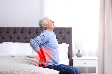 senior man suffering from back pain after sleeping on uncomfortable mattress at home
