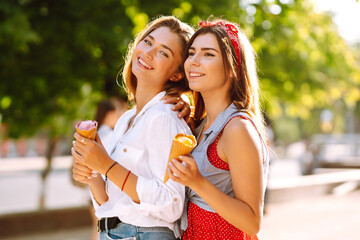 Two young female friends having fun and eating ice cream. Young women enjoy summer and vacation. 