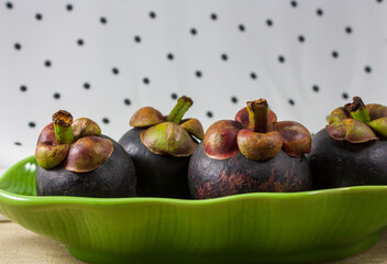 Mangosteen in banana leaf dish polka dot background