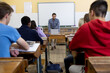 © Wavebreak Media - Rear view of students listening to the teacher