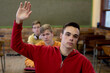 © Wavebreak Media - Front view of student raising his hand in class