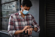 © Wavebreak Media - Caucasian man wearing a covid19 coronavirus mask outside and looking at his watch
