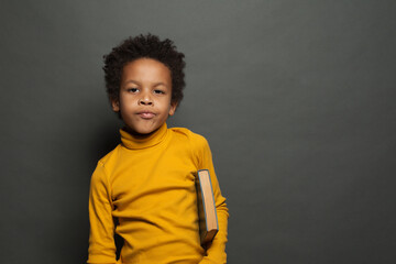 Portrait of black child student with book on chalkboard background