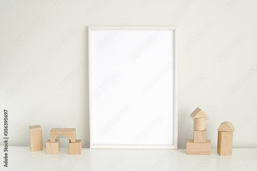 White frame mockup for nursery or kids room, blank photo frame and wooden cubes. - obrazy, fototapety, plakaty 