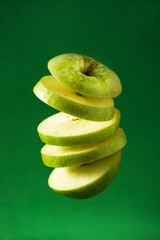 Poster - Sliced green apple cut in the air on green background