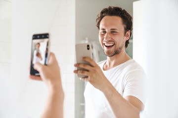 Wall Mural - Attractive young man standing in front of the bathroom mirror