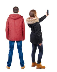 Sticker - Back view of couple in winter jacket photographed on a mobile phone in winter jacket.