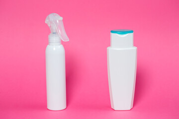 Two white bottles with shampoo for hair, body gel, spray for the skin on a pink background