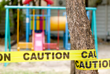 Closed Children Playground Blockade By Bright Yellow Tape With Caution Signs.