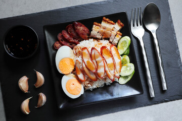 Thai dish '' Khao mu daeng '' or red sauce pork stew with rice in the black plate on the black table in the restuarant