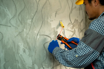Poster - Electricians use wire cutting equipment,Electrician cuts off part of the power cable when installing a switchboard in a residential building.