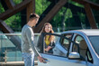 © zinkevych - Young pretty woman opening the car door, talking to the young man and smiling