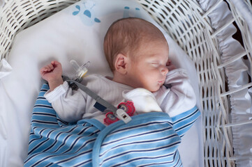 A premature baby sleeps on a moses basket.