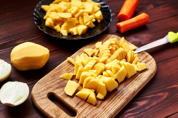 peeled sliced raw potatoes on a wooden board. Preparing vegetables for cooking.