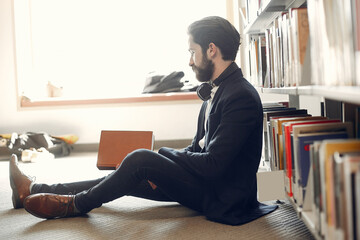 Wall Mural - Man in a library. Guy in a black suit. Student with a books.