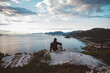 © Cavan Images - Man sitting on a rock looking at sea view