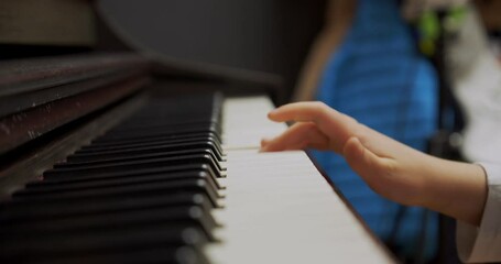 Wall Mural - Little girl playing piano at home. Kid play piano in living room. Child learning piano at home. Music lesson, close up of hand, side view.