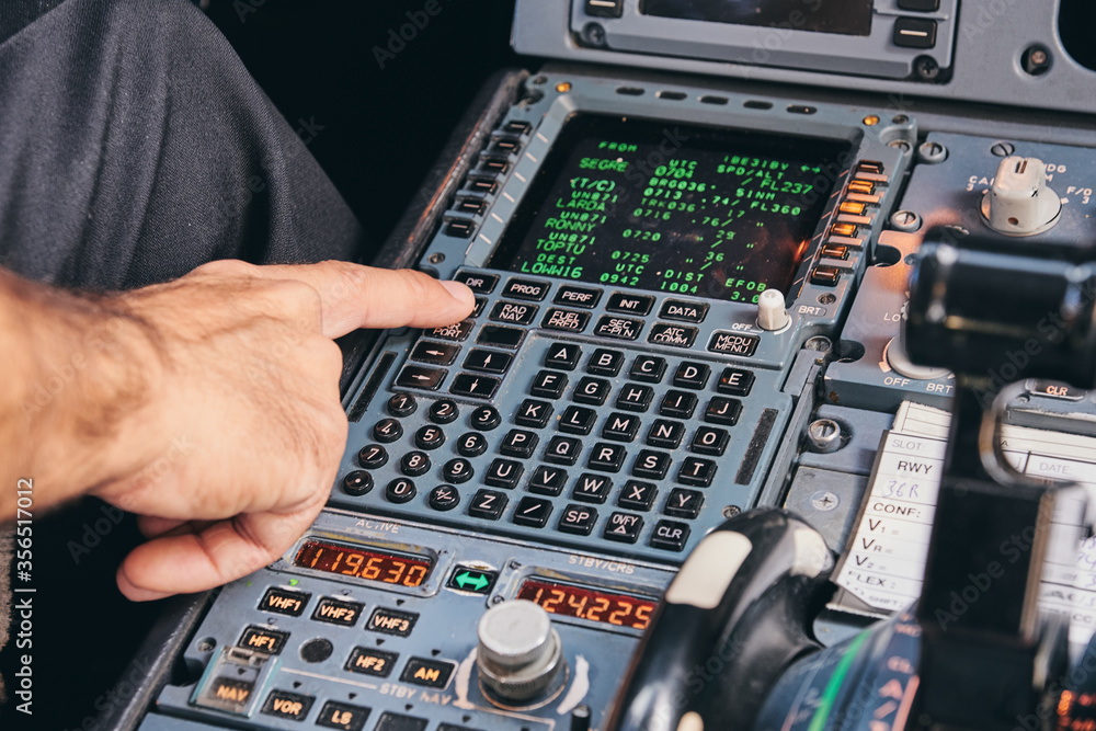 Crop anonymous male pilot using keyboard of flight management system in ...