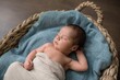 © Gustavo Pozo/ADDICTIVE STOCK - Top view of newborn baby wrapped in cloth lying on soft blanket and sleeping in wicker basket on floor at home