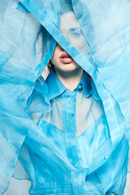 Alluring Model Wearing Transparent Blue Blouse And Covering Face With Textile While Looking At Camera In Studio