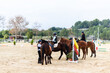 © Jordi Janau/ADDICTIVE STOCK - Teen jockeys in helmets communicating with each other while riding obedient horses on sandy dressage arena during lesson in equestrian school