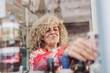 © Luis Manuel Matias/ADDICTIVE STOCK - Happy adult woman with curly hair selling cheese in local food delicatessen store