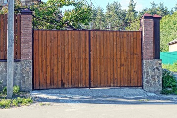 one large closed wooden gate made of brown planks on a rural street