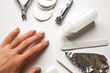 Close up shot of a hand with regrown gel nail polish among nail polish removal kit