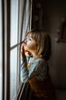 © Rafa Cortes/ADDICTIVE STOCK - Adorable little girl in casual clothes looking out window while resting in cozy room at home