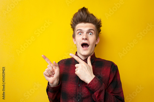 Fotografía shocked guy with a funny hairstyle is surprised at a yellow isolated background,
