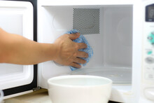 Using A Cloth To Clean A Microwave Oven In Kitchen Room