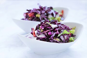   Red cabbage salad. fresh vegetable salad in white ceramic plates on a light marble background.Vegetable salad ingredients.Healthy eating and diet concept.