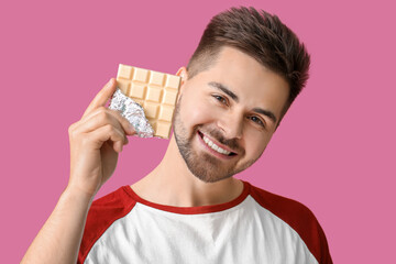 Sticker - Handsome young man with tasty chocolate on color background