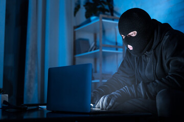 Fototapete - Masked hacker downloading private information using pc
