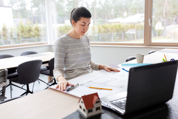 Wall Mural - remote job, business and people concept - young female architect with blueprint of house project and laptop computer working at home office