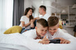 © JustLife - Two little brothers are playing games on the phone. Beautiful boys enjoying at home.