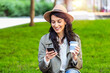 © Graphicroyalty - Beautiful young woman with mobile phone and cup of coffee outdoors. Cheerful young woman wearing coat outdoors, holding takeaway coffee cup, using mobile phone