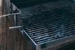 Part of dirty Barbecue Grill Grate after cooking. Empty grill grate. Side view of a barbecue grill grate with lava stones beneath it, lit by sunlight. Cooking on the balcony. Meat cooking device