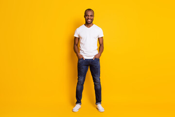 Wall Mural - Full length body size view of his he nice attractive content cheerful cherry guy holding hands in pockets isolated over bright vivid shine vibrant yellow color background