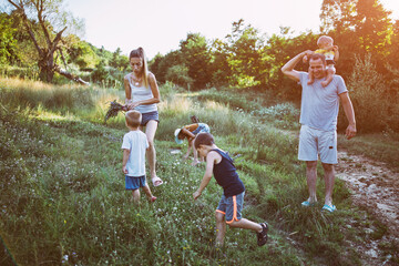 Mother and father  with children picking flowers in rural countryside nature.