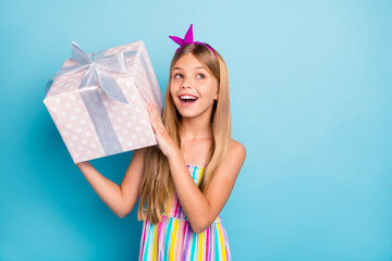 Sticker - Portrait of positive cheerful kid girl hold big gift box she get receive anniversary shake want know what inside wear stylish trendy outfit isolated over blue color background