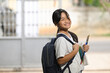 © Prathankarnpap - A schoolgirl is holding painting equipment and carrying a school bag while standing and waiting for a school bus.