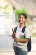 © Prathankarnpap - A schoolgirl is holding painting equipment and carrying a school bag while standing and waiting for a school bus.